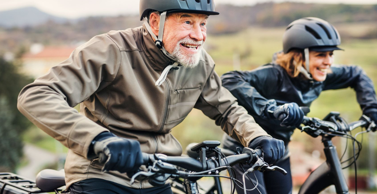 A group of seniors in safety helmets riding bicycles together in a lush outdoor setting.
