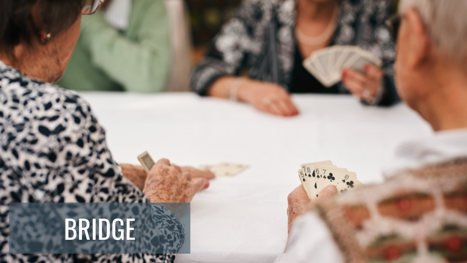 A group of members sitting at a table playing the card game, Bridge.