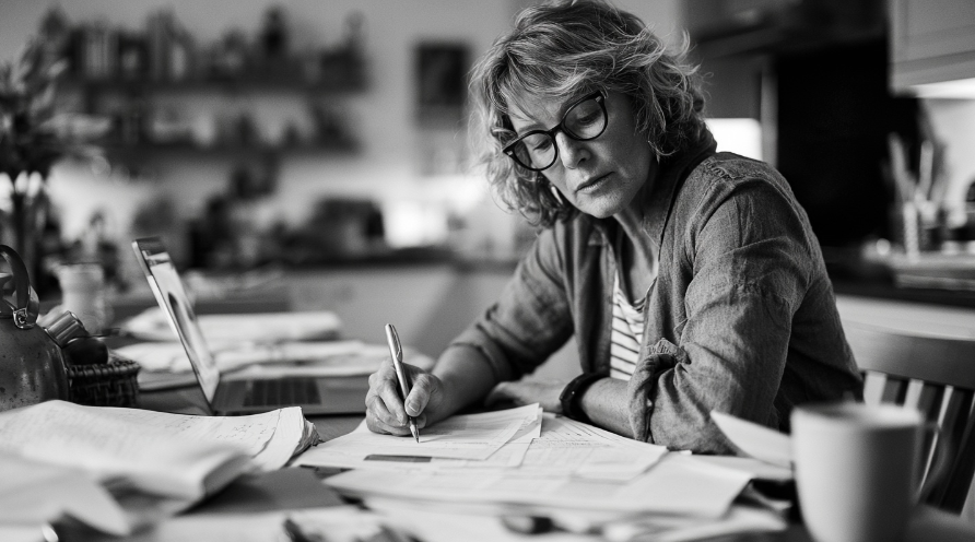 A photo of a person sitting at a table working out a routine budget.