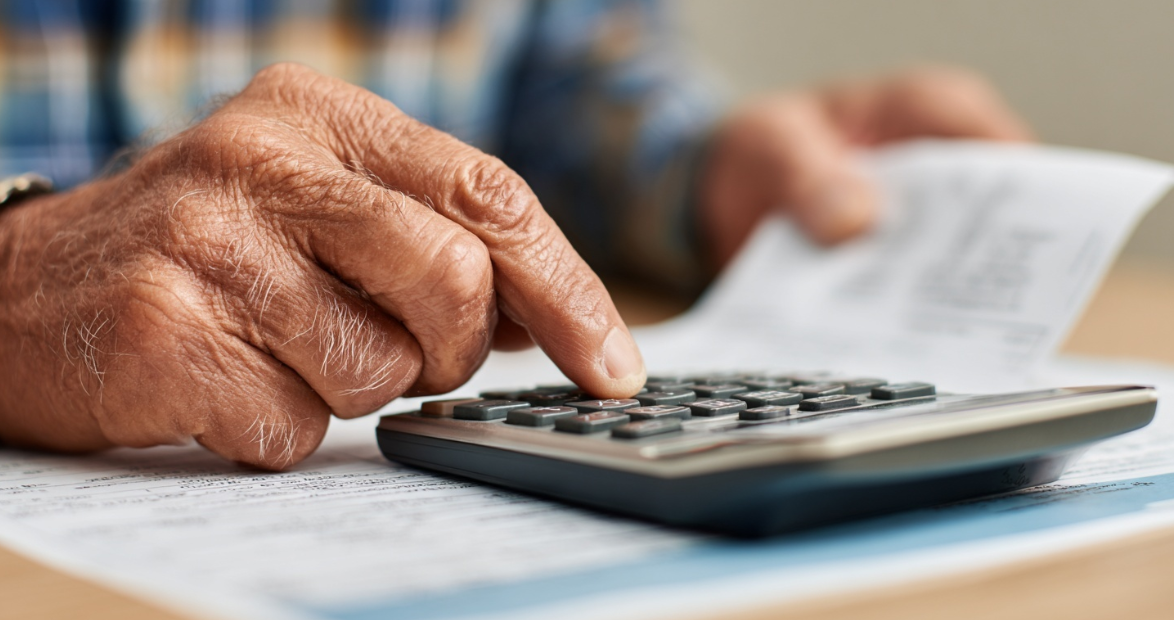 Close up photo of a person typing numbers into a calculator used for budgeting monthly expenses.