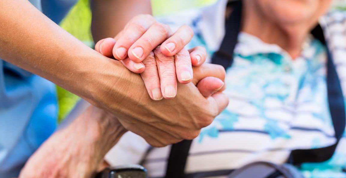 Two people holding hands, each cupped inside one another's in a supportive way.