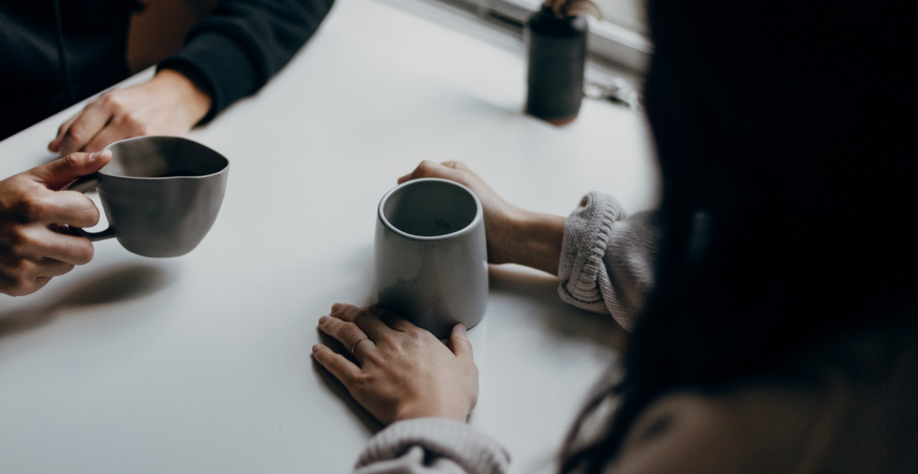 A couple of members sitting with coffee having a discussion near a cozy window setting.