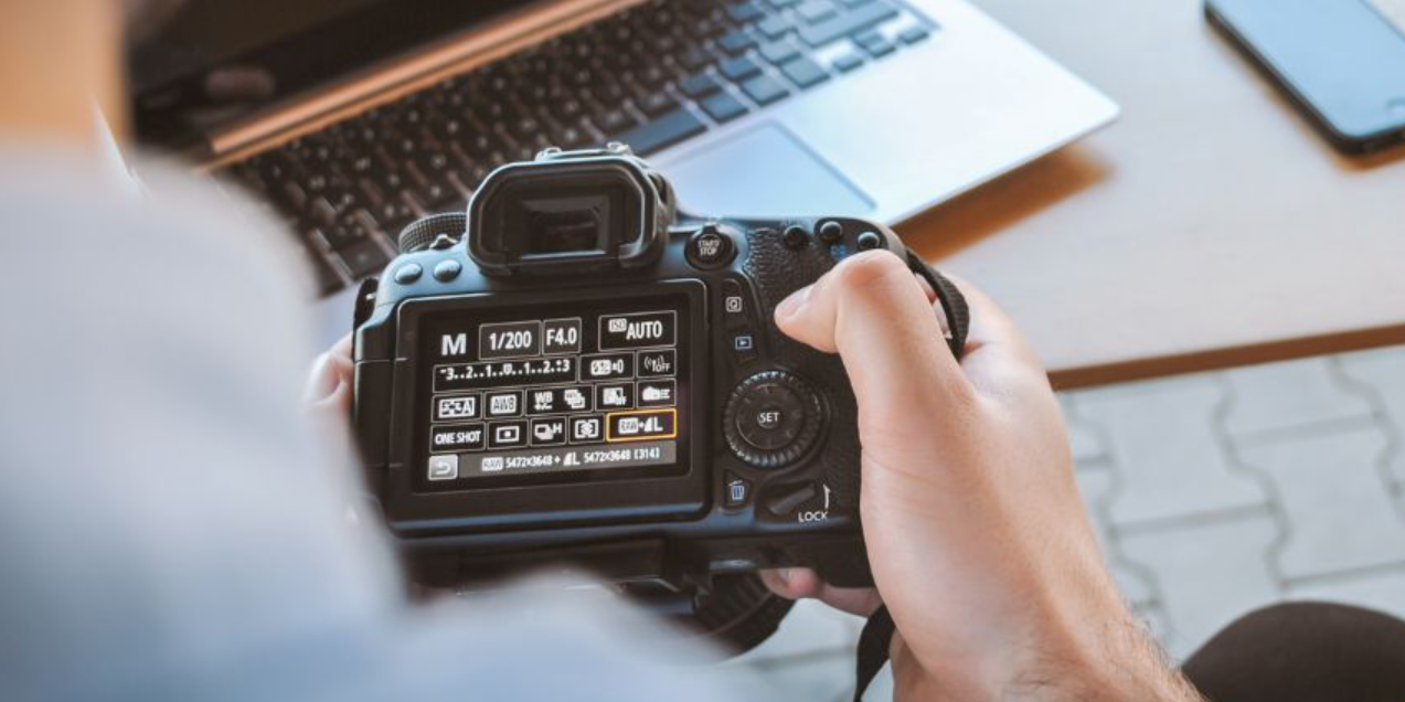 A person browsing through the manual settings of a digital camera while seated at their computer.