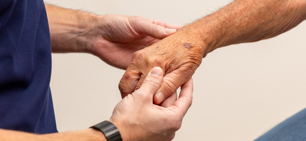 A photo of a registered nurse observing and screening the arm of a patient for skin cancer.