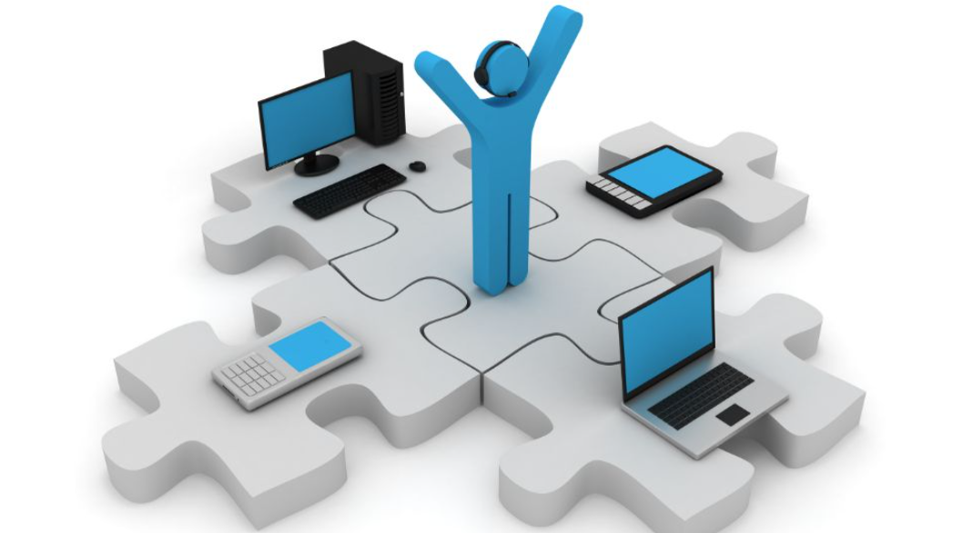A computer generated graphic of a stick-figured person standing on a puzzle piece with conjoined puzzle pieces that have individual technology items on each piece. A desktop computer, a mobile phone, a tablet, and a personal laptop.